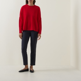 Model wearing Oska navy trousers in slim fit, styled with a red knit sweater and black ballet flats.