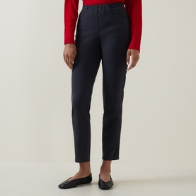 Model wearing Oska navy trousers in lyocell-cotton blend, tapered leg, styled with a red top and black flat shoes.