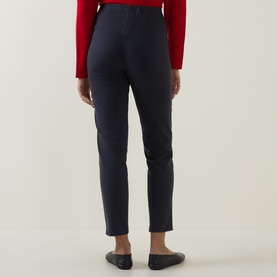 Model wearing Oska navy trousers in slim-fit silhouette, styled with a red top and black flat shoes, rear view.