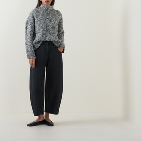 Model wearing Oska Wide Leg Cropped Trousers in black with grey marl knit jumper and black flat mules.