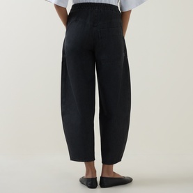 Model wearing Oska Wide Leg Cropped Trousers in black, rear view showing elasticated waistband and tapered silhouette, styled with black ballet flats.