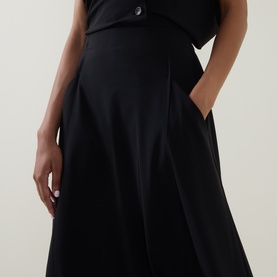 Model wearing Oska black wide-leg trousers in polyamide-elastane blend, with hand in side pocket, paired with black top.