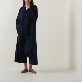 Model wearing Oska Draped Wide Cropped Trousers in navy, styled with matching navy shirt and taupe flat shoes.