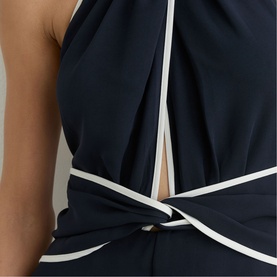 Model wearing Reiss blue halterneck dress with white contrast trim detailing at crossover bodice and waist wrap