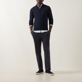 Model wearing John Smedley Tapton Extra Fine Knit Half-Zip Sweater in blue, styled with a white shirt, dark trousers and navy trainers.