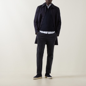Model wearing John Smedley Tapton Extra Fine Knit Half-Zip Sweater in blue, styled with a navy overcoat, white shirt and grey trousers.