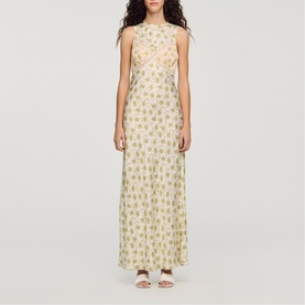 Model wearing Sandro Womens French Dress in olive and ecru floral print, sleeveless maxi length, styled with white strappy heels.