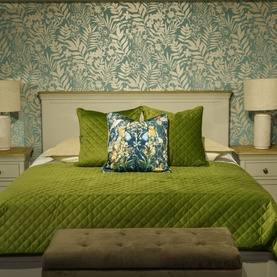Fever + Hue Velvet Quilted Throw in Moss Green draped over a double bed, styled with floral cushions and botanical wallpaper backdrop.
