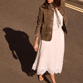 Model wearing white lace-hem midi slip dress with brown suede jacket, styled with tan strappy sandals