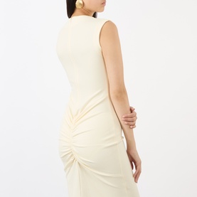 Model wearing Jacquemus off-white sleeveless dress with ruched side detail, styled with gold earrings, back view shown.