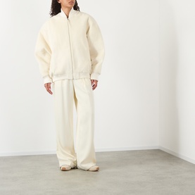 Model wearing Jacquemus off-white zip-up jacket with matching wide-leg trousers and cream trainers