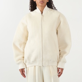 Model wearing Jacquemus off-white zip-up bomber jacket with ribbed cuffs and hem, styled with matching wide-leg trousers