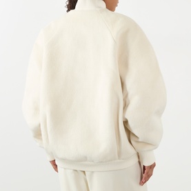 Model wearing Jacquemus off-white fluffy zip-up jacket, back view, styled with matching off-white trousers.