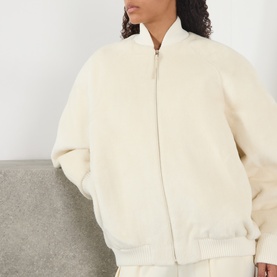 Model wearing Jacquemus off-white fluffy zip-up bomber jacket with ribbed cuffs and hem, styled with matching trousers