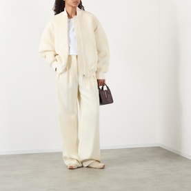 Model wearing Jacquemus off-white jacket with matching wide-leg trousers, styled with a small dark brown top-handle bag.