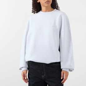 Model wearing Jacquemus grey sweat top in Grey 950, relaxed fit with crew neck, styled with dark jeans