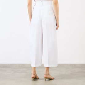 Model wearing Jacquemus white wide-leg cropped cotton trousers, rear view, styled with nude strappy heeled sandals
