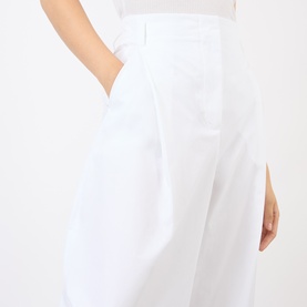 Model wearing Jacquemus white cotton wide-leg trousers with pleat detail and side pockets, styled with a white top