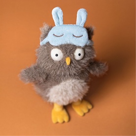 Jellycat grey fluffy owl plush with yellow feet and blue sleeping bunny ear eye mask, small size, on orange background