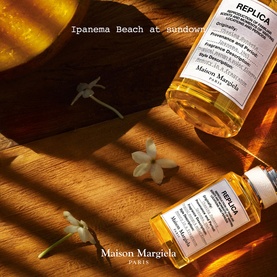 Maison Margiela Replica Ipanema Beach at Sundown EDT bottles on warm wooden surface with jasmine flowers, golden sunlight