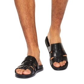 Model wearing KG by Kurt Geiger black leather slide sandals with woven multi-strap upper and flat sole.