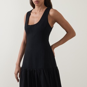 Model wearing Odd Muse Dropped Waist Flared Dress in black, showing fitted ribbed bodice with scoop neck and tank straps, flared skirt hem visible.
