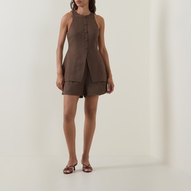 Model wearing Odd Muse Solid Pleated Shorts in mushroom with matching sleeveless waistcoat top and tan flat sandals.