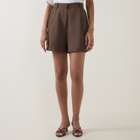 Model wearing Odd Muse Solid Pleated Shorts in Mushroom, high-rise with front pleats, styled with brown strappy heels