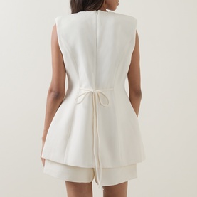 Model wearing Odd Muse Solid Tailored Ecru Waistcoat, showing rear self-tie waist detail and concealed zip, styled with matching shorts.