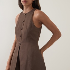 Model wearing Odd Muse Solid Cinched Waistcoat in Mushroom, sleeveless with crew neck, front button fastening and front split detail.