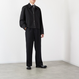 Model wearing Our Legacy black wool casual jacket with matching black wide-leg trousers and black leather shoes.