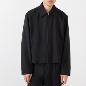 Model wearing Our Legacy black wool casual jacket with full-length zip fastening, styled with matching black trousers.