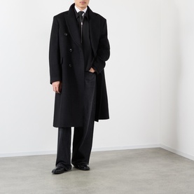 Model wearing Our Legacy black double-breasted wool overcoat, styled with dark trousers, zip-neck top and black dress shoes.