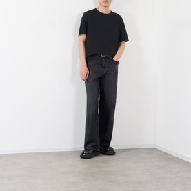 Model wearing Our Legacy black cotton T-shirt with black wide-leg jeans and black leather loafers.
