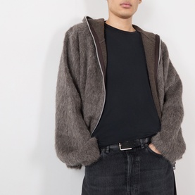 Model wearing Our Legacy black cotton T-shirt, styled with a taupe fluffy zip-up jacket and dark jeans.
