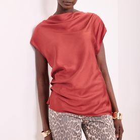 Model wearing red sleeveless drape neck top with ruched side detail, styled with leopard print trousers and gold bracelet