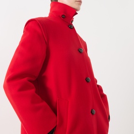Model wearing Max Mara Weekend red wool coat with high funnel neck and black button fastening, cropped side view