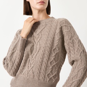 Model wearing a taupe cable-knit crew-neck sweater with textured stitch detail, cropped close-up shot