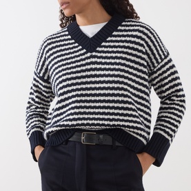 Model wearing Max Mara Weekend navy and white stripe wool V-neck sweater, styled with dark tailored trousers and a belt.