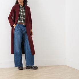 Model wearing Max Mara Weekend khaki silk shirt styled with burgundy longline coat, wide-leg blue jeans, and chunky black boots.