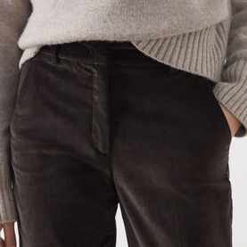 Model wearing Max Mara Weekend dark brown corduroy trousers, styled with a grey knit jumper. Close-up detail of waistband and pocket.