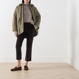 Model wearing Max Mara Weekend dark brown cotton trousers, styled with an olive oversized jacket, grey knit, and brown loafers.