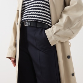 Model wearing Max Mara Weekend Ultramarine wool trousers, styled with a beige trench coat, black belt, and striped knit top.