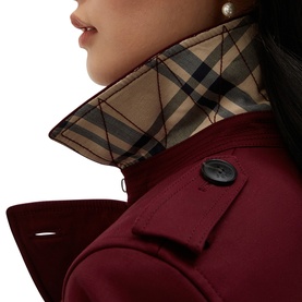 Model wearing Hobbs fig purple coat with check-lined collar and black button detail, pearl earring visible