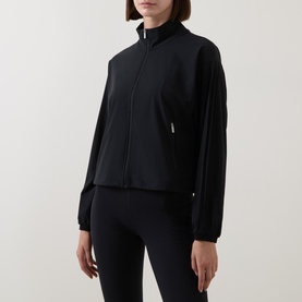 Model wearing Sweaty Betty black zip-up jacket with funnel neck, styled with matching black leggings.