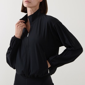 Model wearing Sweaty Betty black zip-up bomber jacket with funnel neck, styled with matching black bottoms