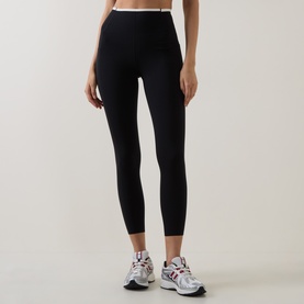 Model wearing Sweaty Betty black high-waist leggings, styled with white and silver chunky trainers.