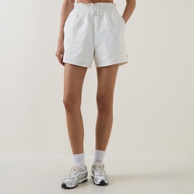 Model wearing Sweaty Betty Lily White shorts with elasticated waist, styled with white socks and grey trainers.