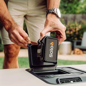 Solo Stove Windchill 47 Cooler & Fan in black being placed onto a surface outdoors, shown with lid open