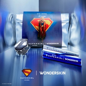 Wonderskin x Supergirl make-up set featuring branded blue lip liner and silver pod, displayed with Superman logo gift packaging.